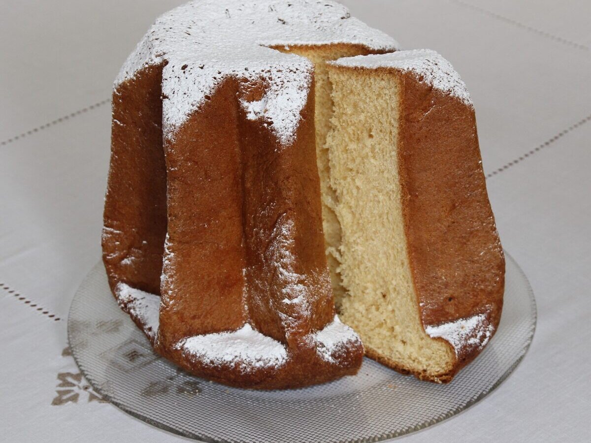 A star-shaped pandoro dusted with sugar, with one slice cut