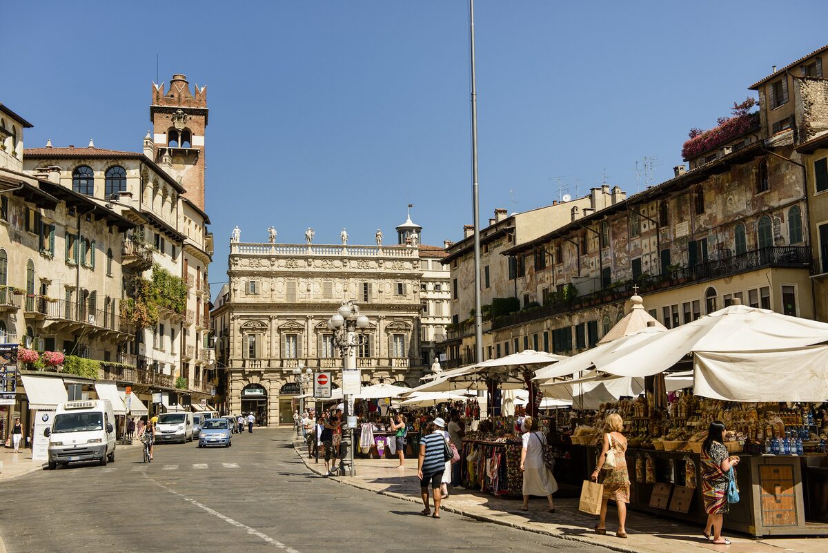 Market stalls on Piazza delle Erbe, with the Gardello tower rising behind