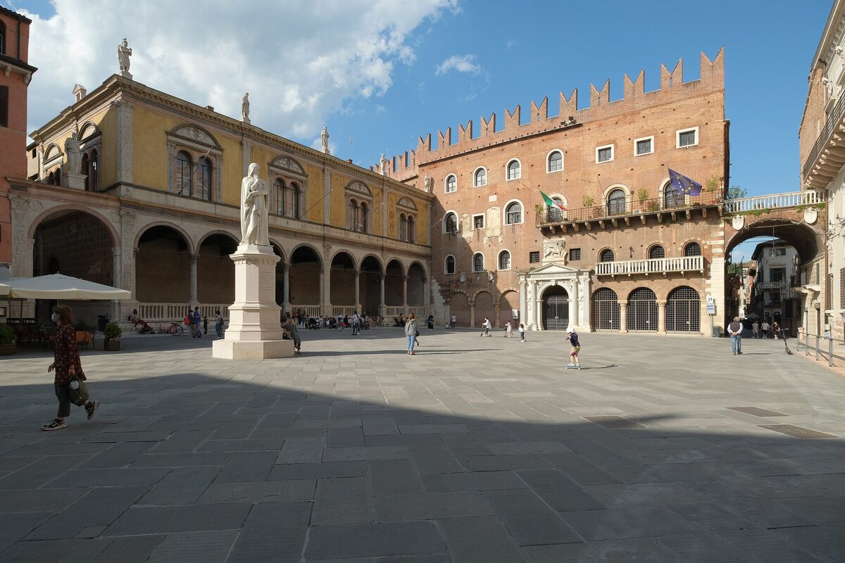 Piazza dei Signori with the Dante statue and a battlemented brick palace