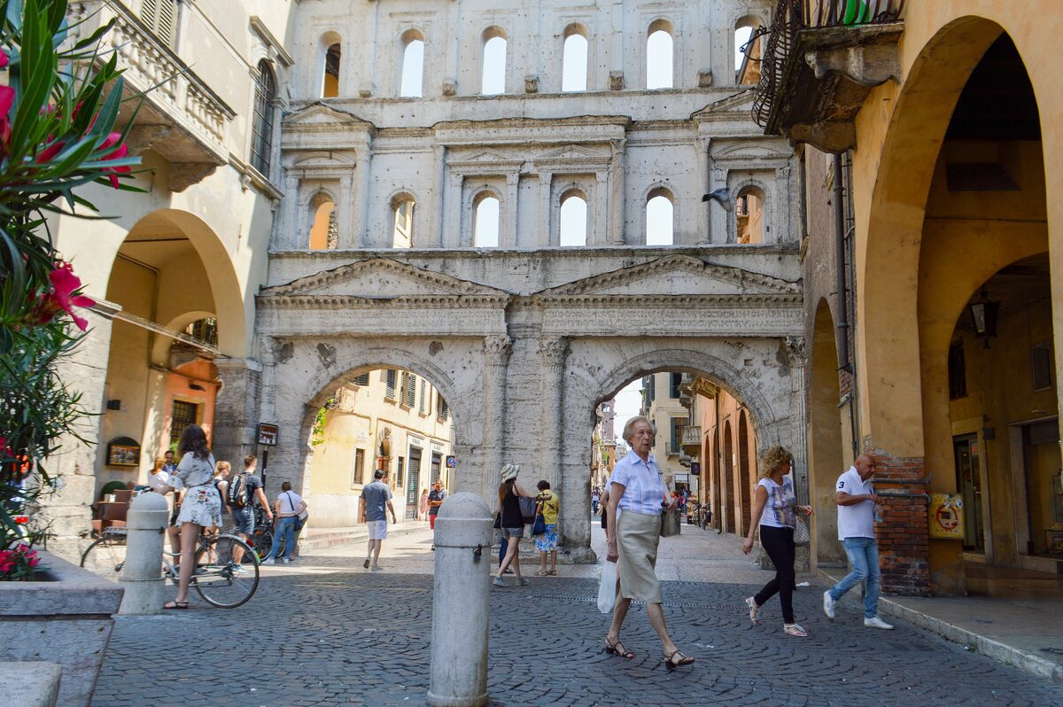 The white Roman facade of Porta Borsari at the end of Corso Porta Borsari