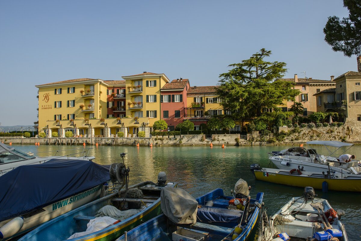 Yellow and orange houses around Sirmione's small harbor and moored boats