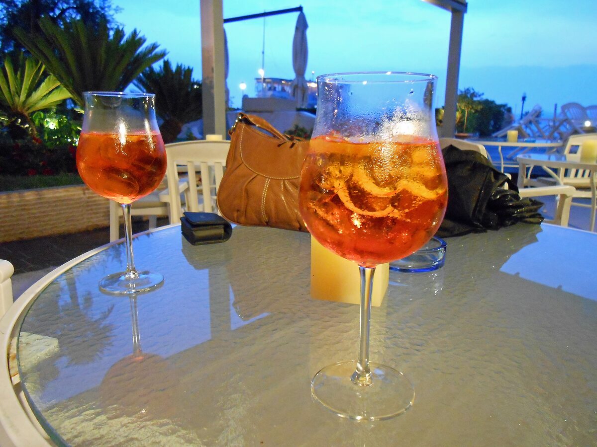 Two glasses of orange spritz on a terrace table at dusk