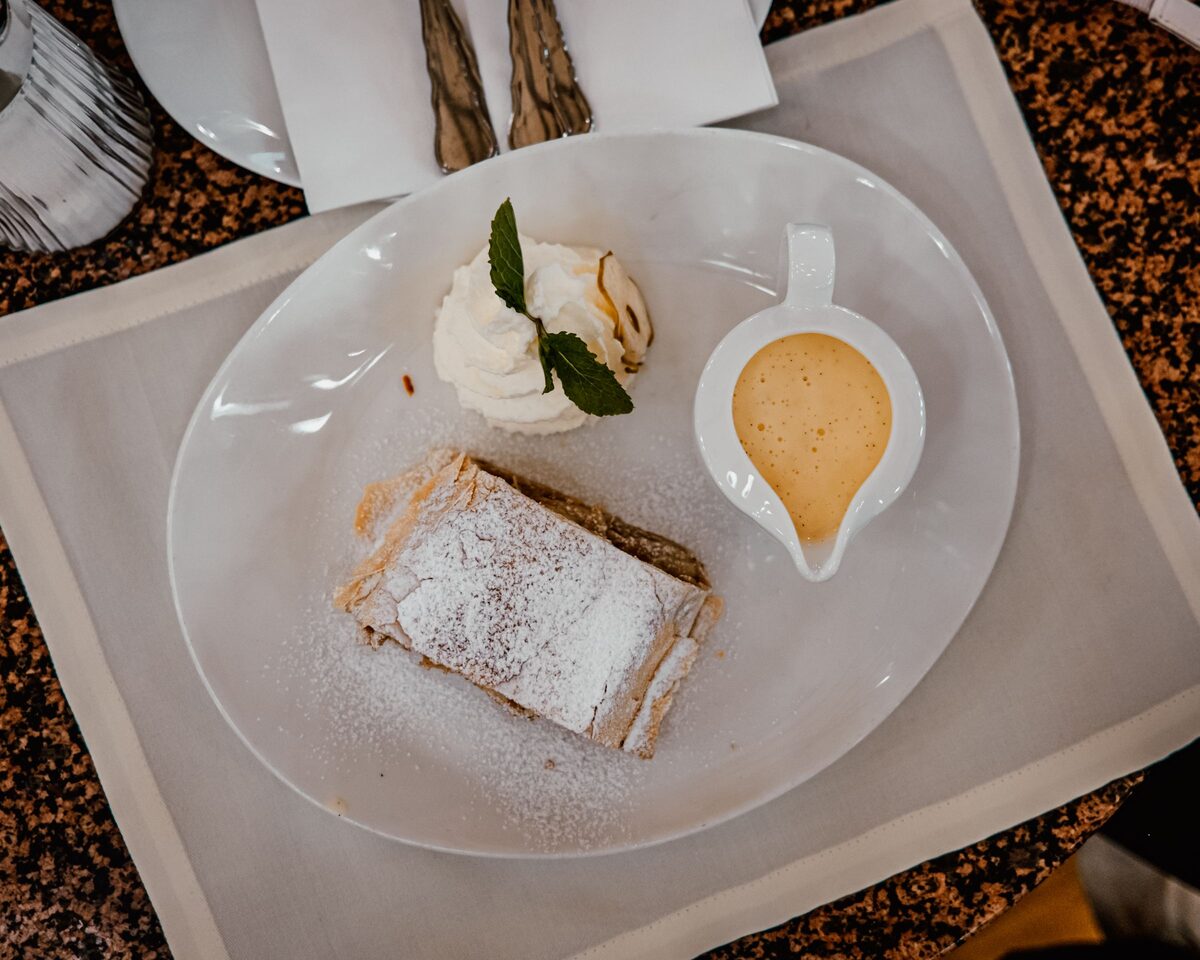 A slice of apple strudel with whipped cream and vanilla sauce