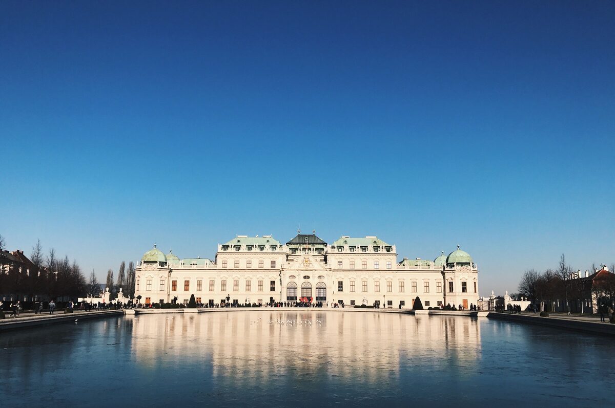 The Upper Belvedere palace reflected in its long pool under a clear blue sky