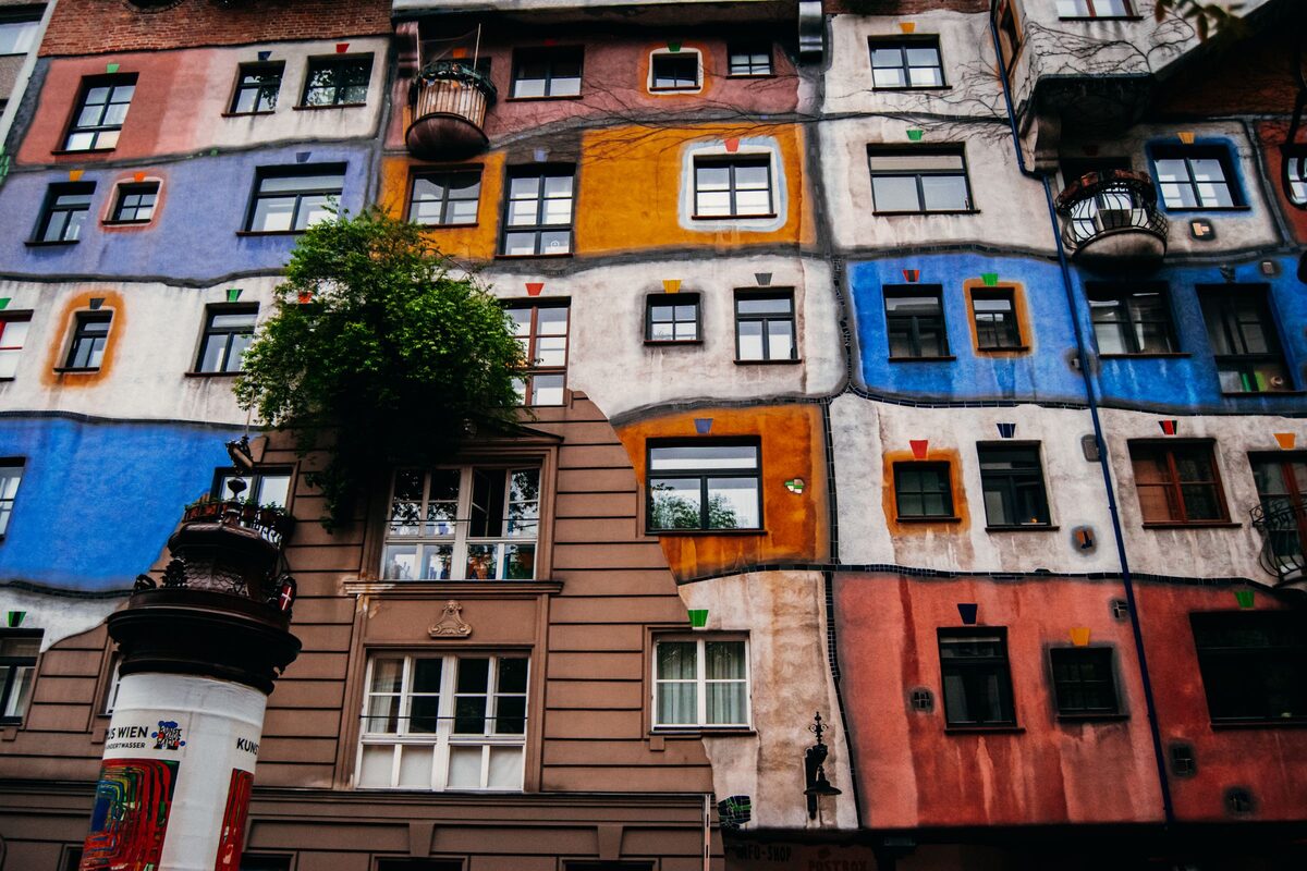 The colorful patchwork facade of the Hundertwasser House in Vienna, with trees growing on its balconies