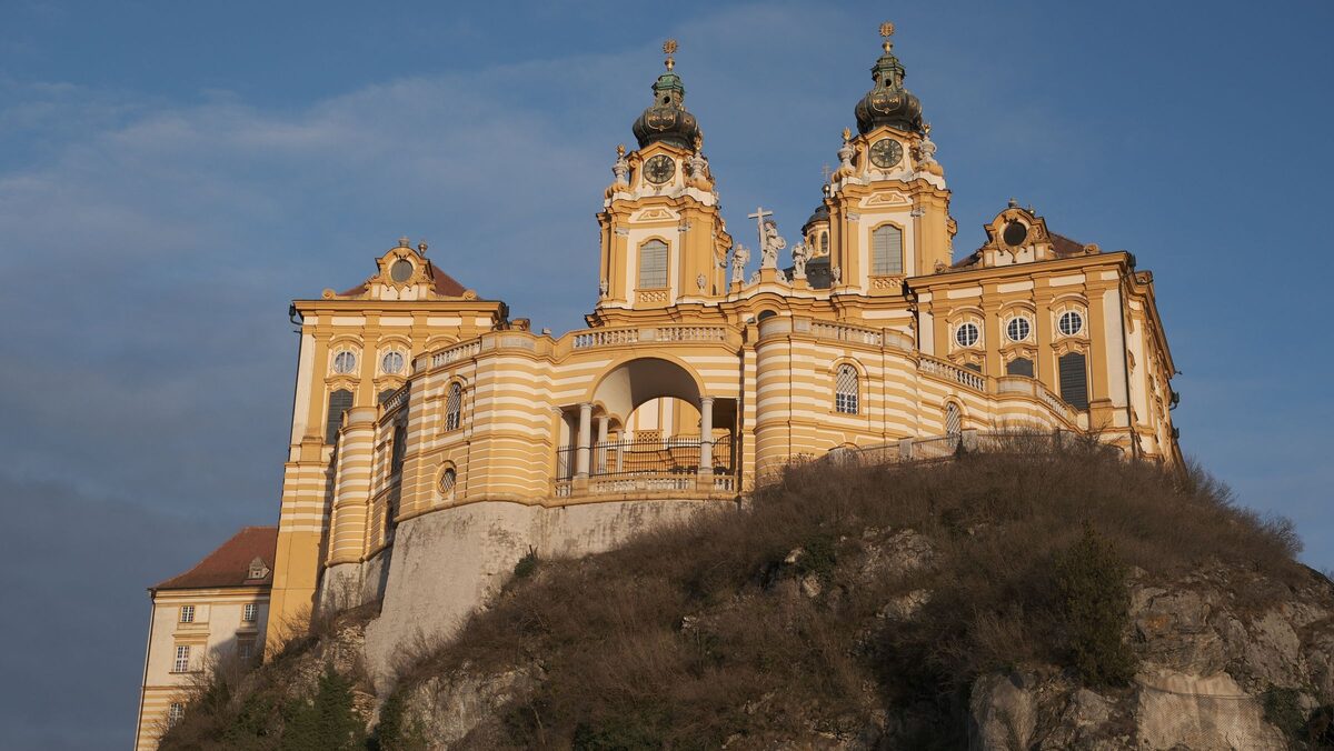 The golden-yellow baroque church of Melk Abbey with its twin towers and dome, on a rock above the town