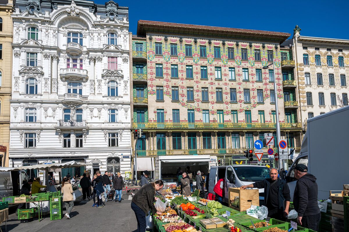Fruit and vegetable stalls at the Naschmarkt in front of ornate Art Nouveau apartment buildings