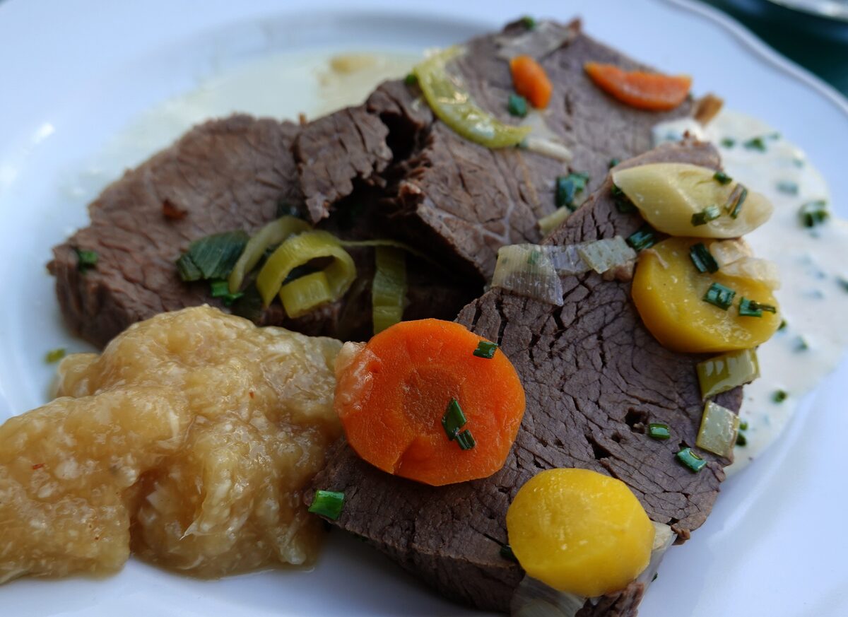 Slices of boiled beef with apple horseradish, carrots and root vegetables on a plate