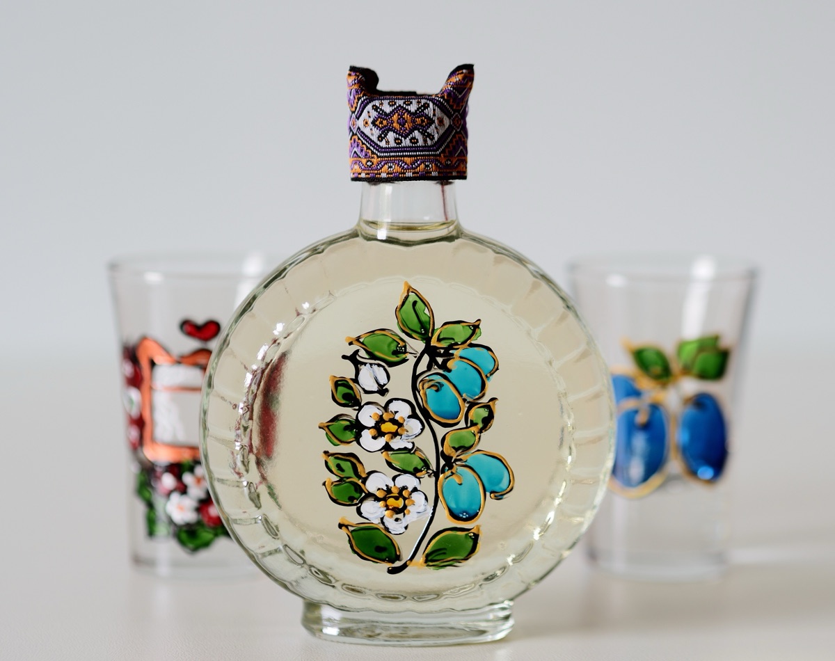 A hand-painted flask of šljivovica plum brandy between two painted glasses