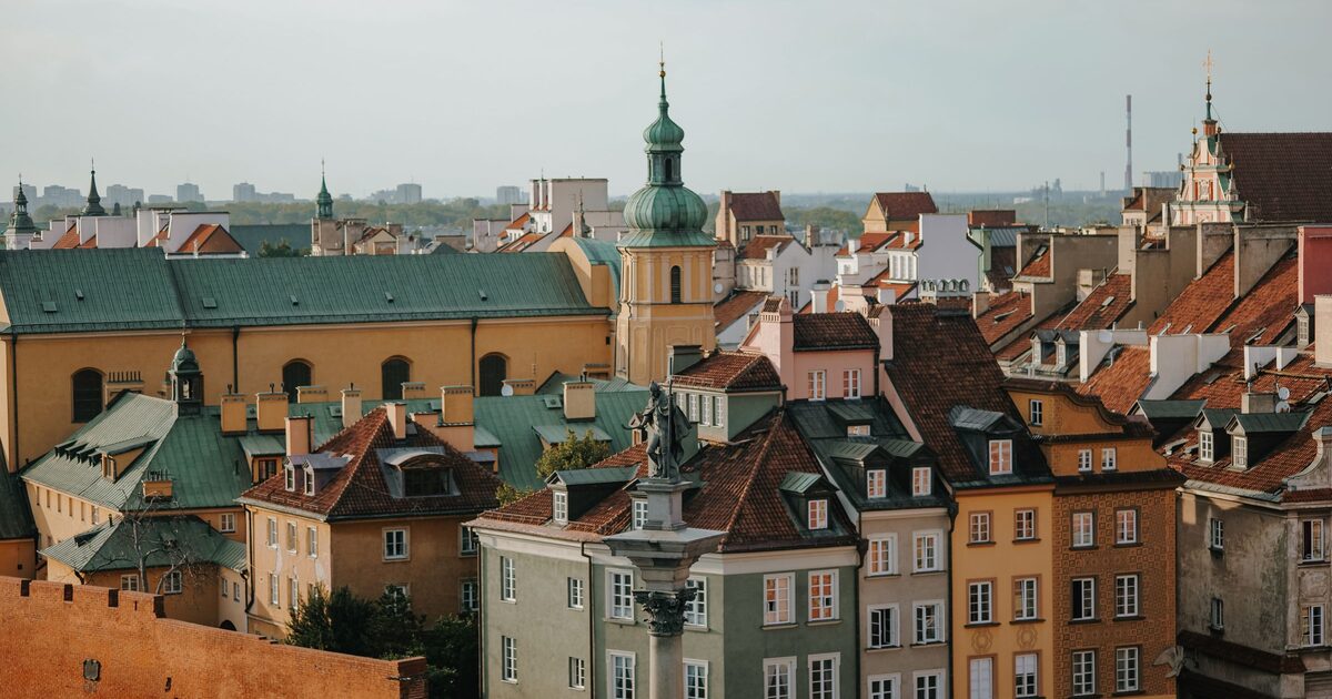 The rooftops of Warsaw's Old Town with green copper domes and church towers, and Sigismund's Column on Castle Square