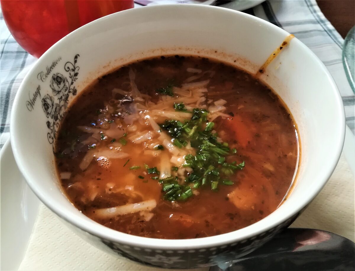 A bowl of Polish flaki tripe soup sprinkled with herbs and grated cheese