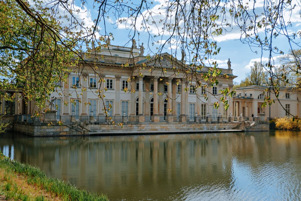 The neoclassical Palace on the Isle in Łazienki Park reflected in its lake, framed by trees