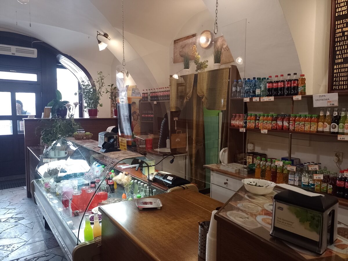 The counter of a Polish milk bar, with a display case of dishes and shelves of drinks