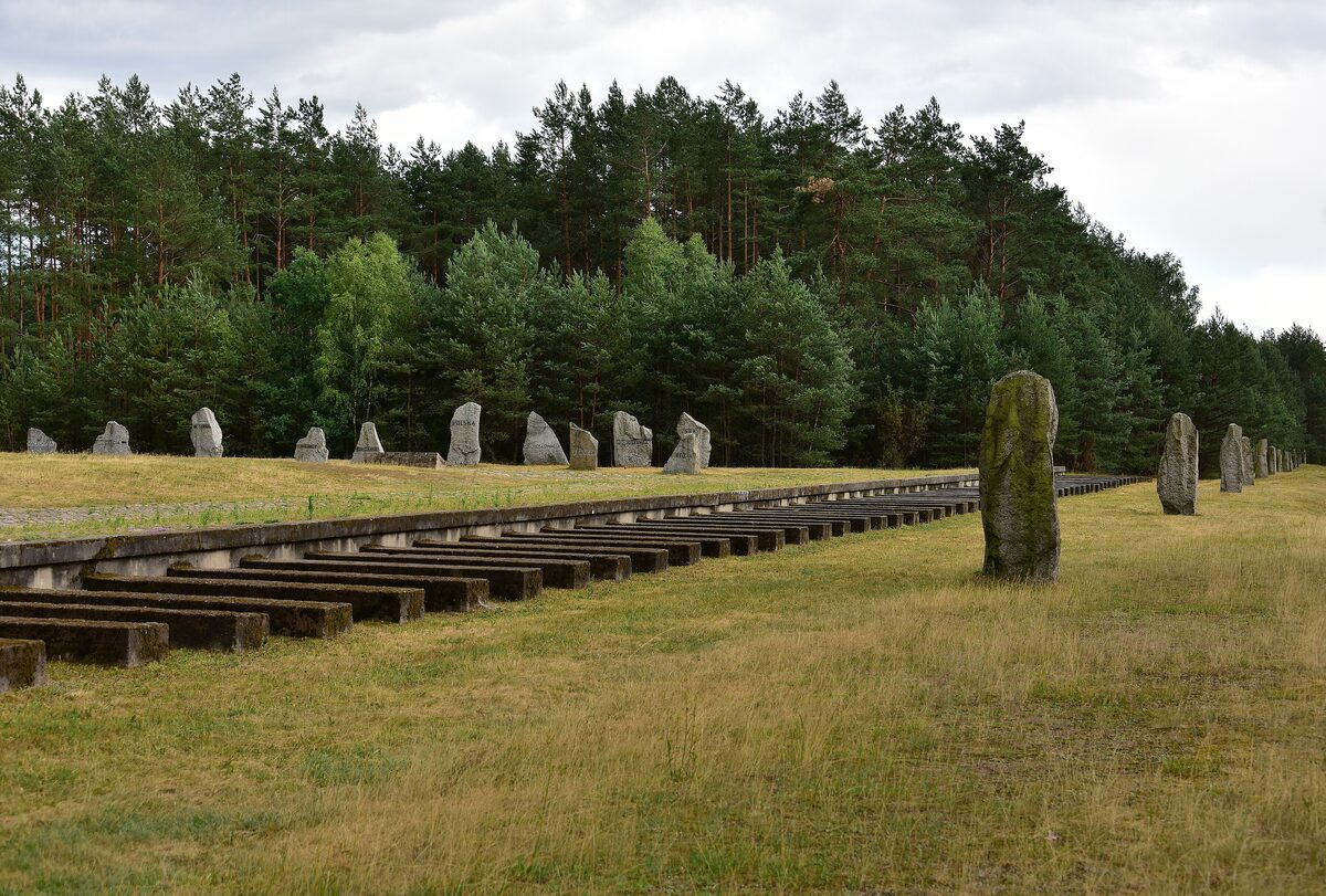 The field of standing stones and concrete railway sleepers at the Treblinka memorial, with pine forest behind