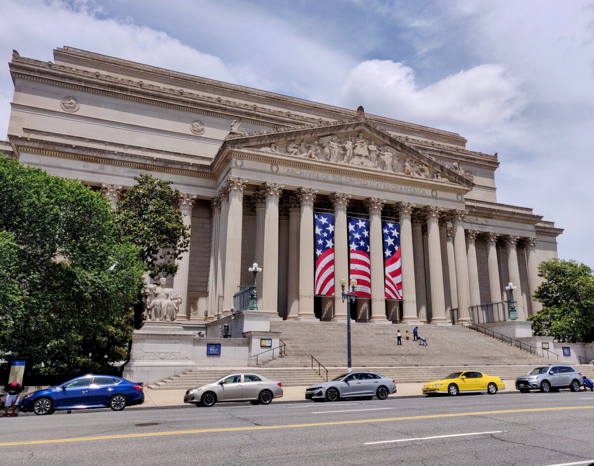 Columned front of the National Archives with flags hanging between pillars
