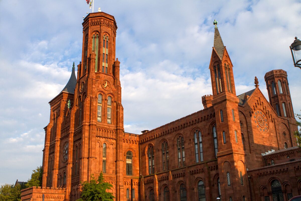 Red sandstone towers of the Smithsonian Castle against a cloudy sky