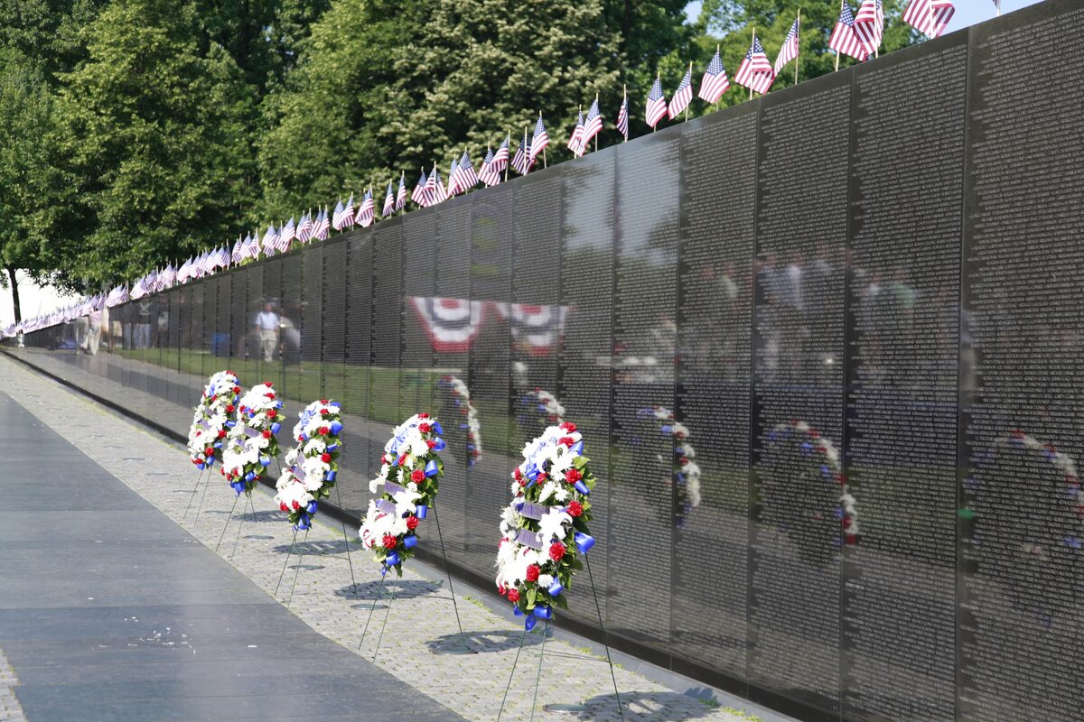 Names on the black granite Vietnam Veterans Wall with wreaths and flags