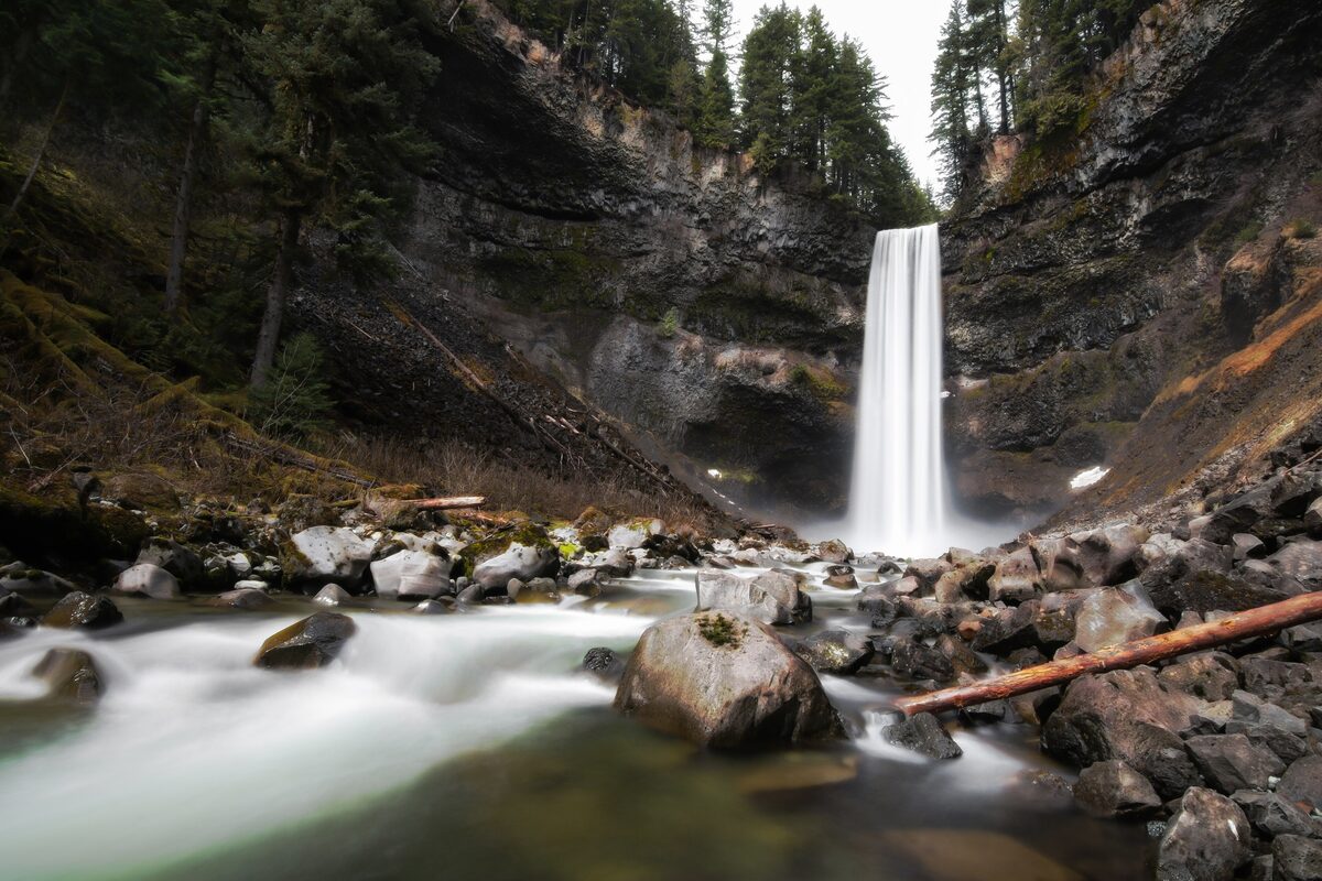 Brandywine Falls dropping into a rocky gorge with a stream in the foreground and forest around