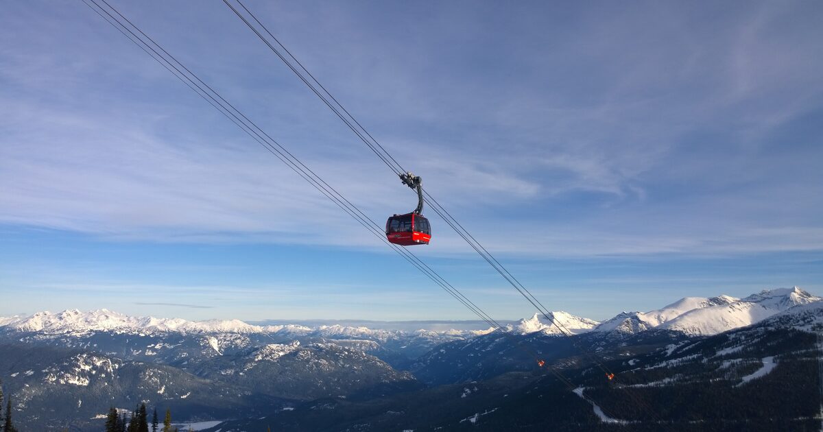 A red Peak 2 Peak gondola cabin on its cables above the snowy Coast Mountains on a clear winter day