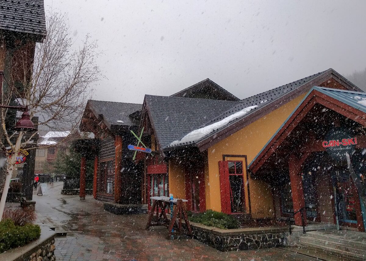 Wooden shop buildings in Whistler Creekside with snow falling