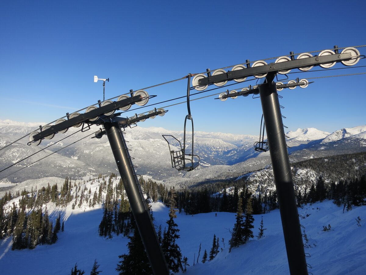 A chair on the Crystal Ridge lift line above snowy slopes and trees on Blackcomb