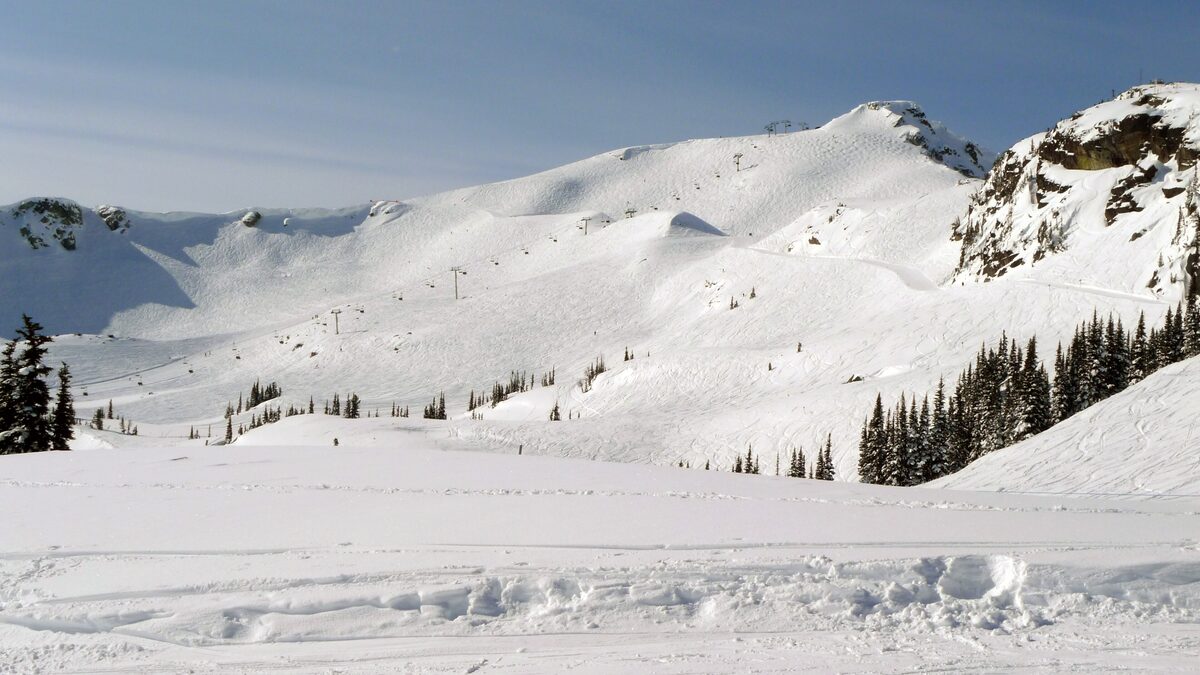The wide snowy Harmony bowl on Whistler Mountain with the Harmony lift line and a rocky ridge on a sunny day