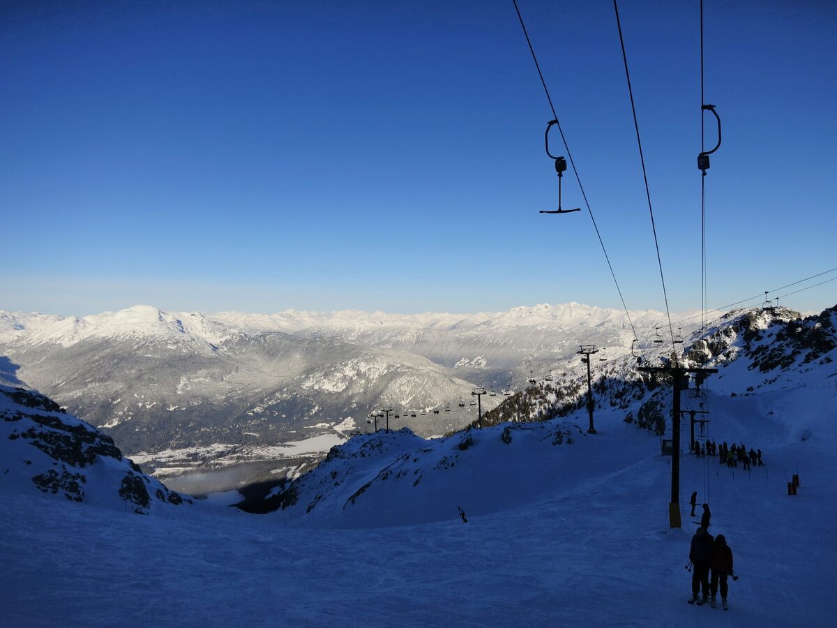 Skiers on the snowy Horstman Glacier slope below the T-bar line, with the valley far below
