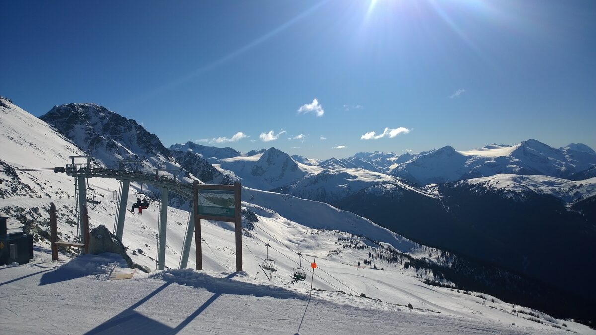 The top of the Seventh Heaven chairlift on a sunny day with snowy slopes and peaks behind