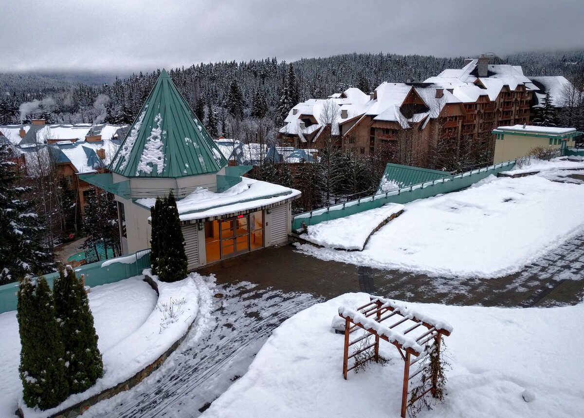 Snow-covered roofs and terraces of the Upper Village hotels with forested slopes behind