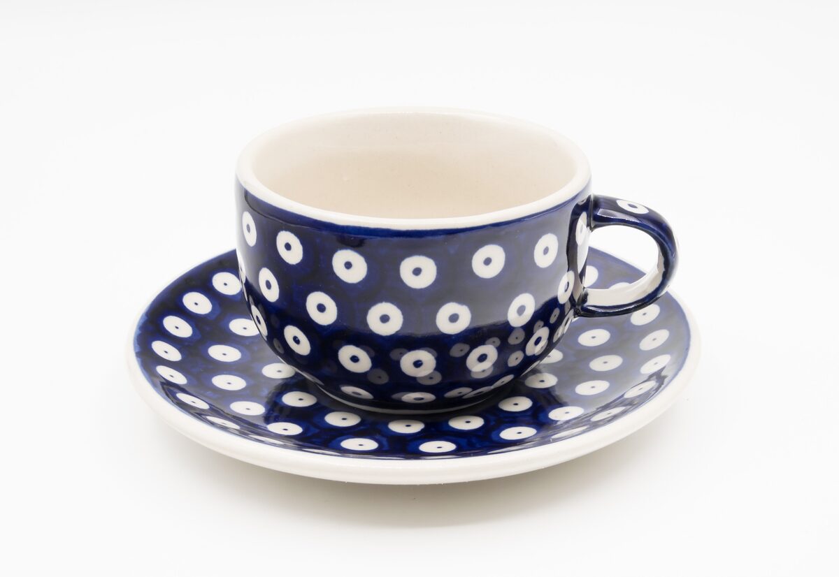 A Bolesławiec stoneware cup and saucer decorated with blue and white peacock eyes