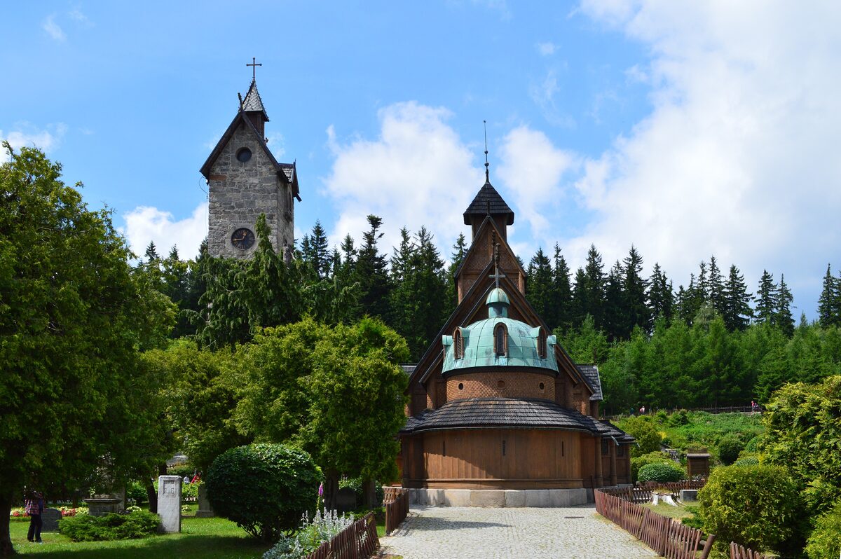 The wooden Wang stave church in Karpacz with its stone bell tower, among trees