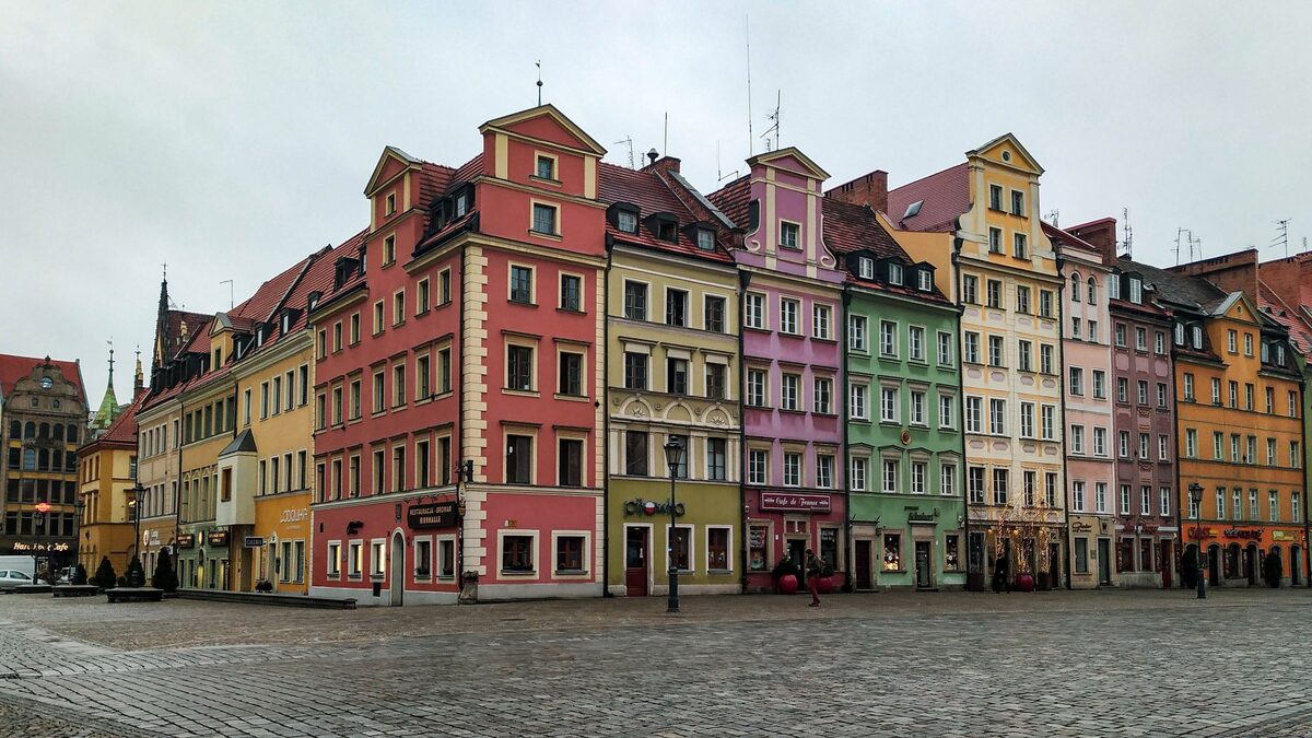 A row of colorful tenement houses with gables on Wrocław's Market Square, on a wet cobbled square