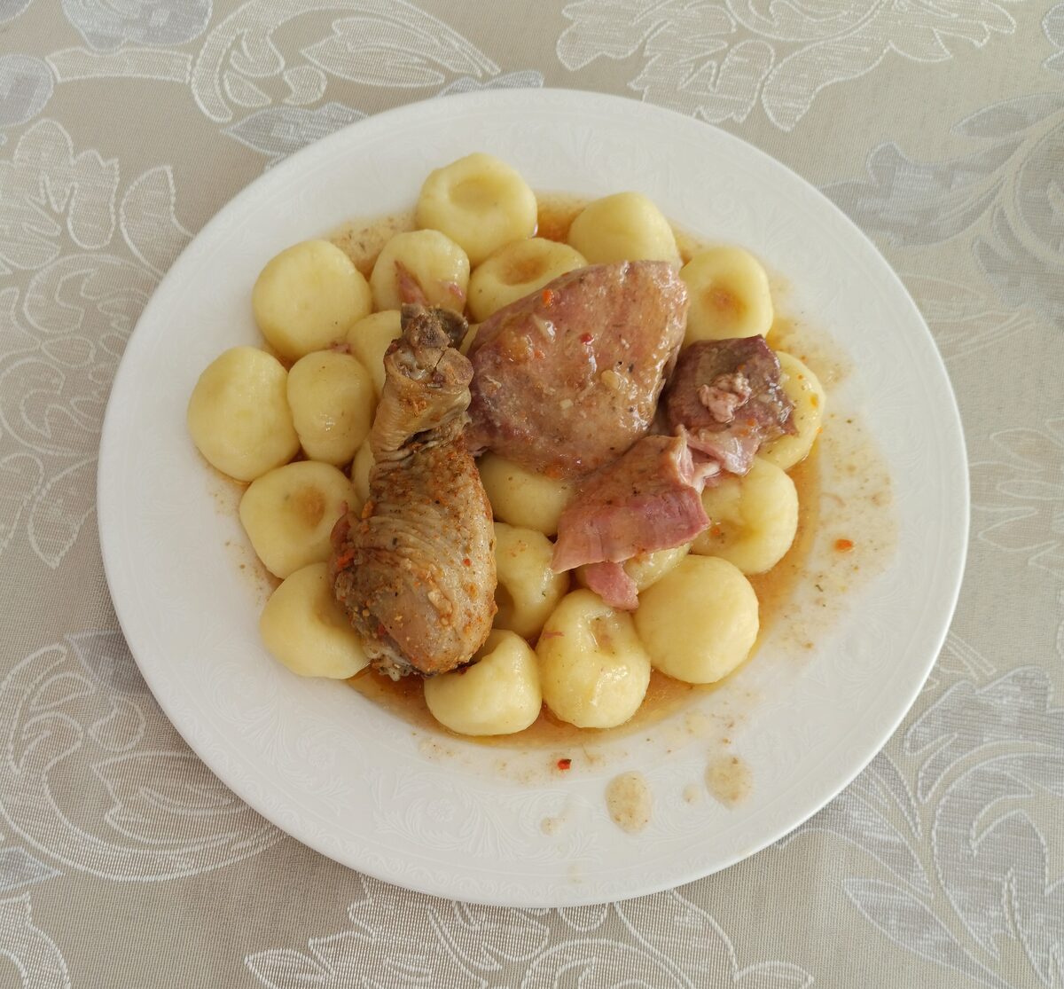 A plate of kluski śląskie, round Silesian potato dumplings, with pieces of meat in gravy