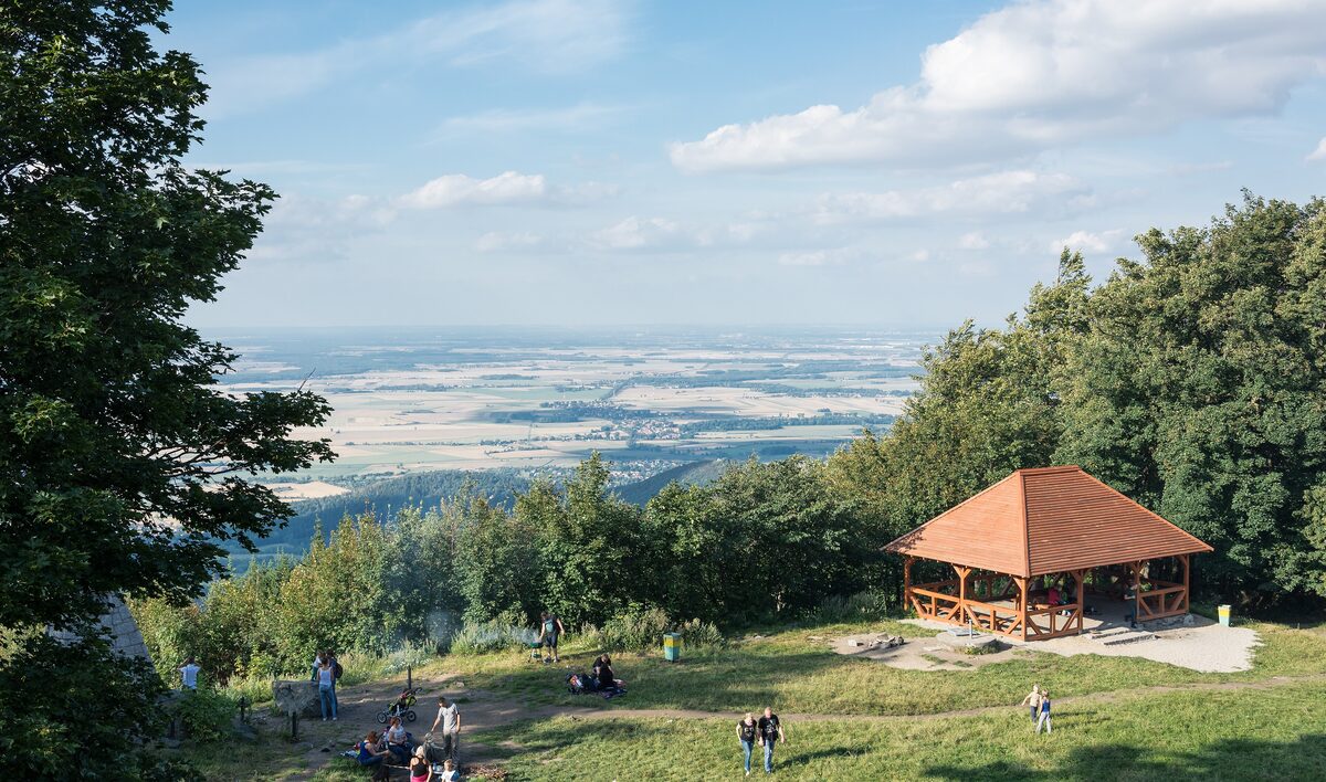 The view from Ślęża over the Silesian plain, with people resting near a wooden shelter