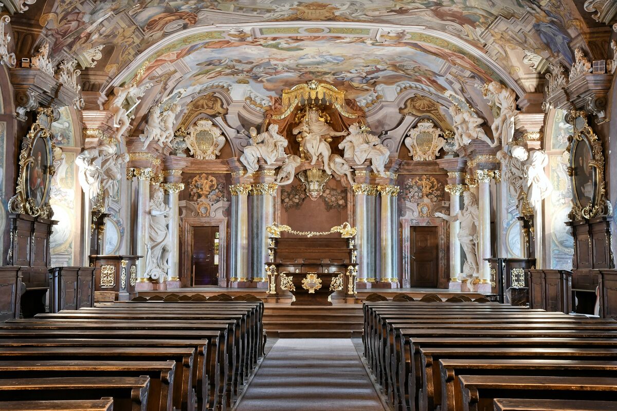 The Aula Leopoldina, a baroque hall with painted ceilings, gilded statues and rows of wooden benches