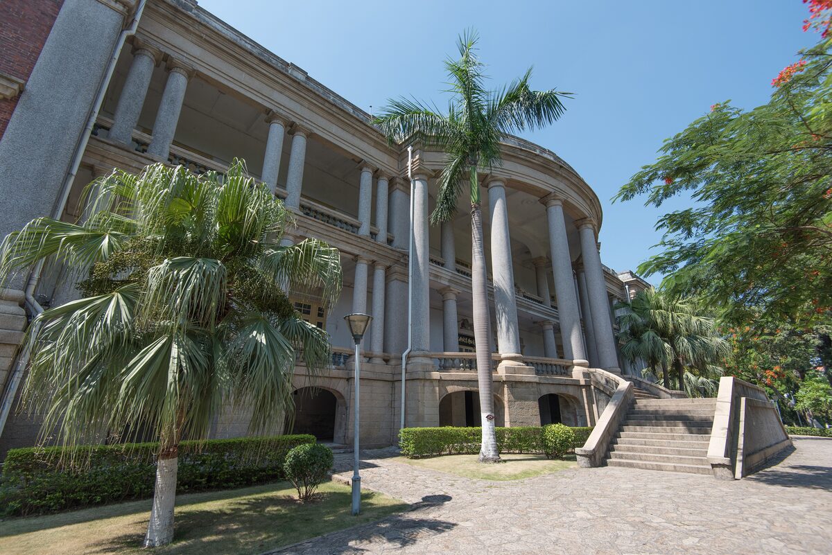 The curved, colonnaded facade of the Bagua Building on Gulangyu, with palm trees and a wide stairway