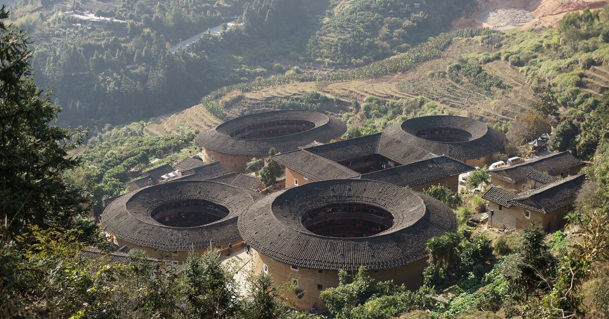 Round Fujian tulou earthen buildings with gray tile roofs seen from the hillside above Tianluokeng village