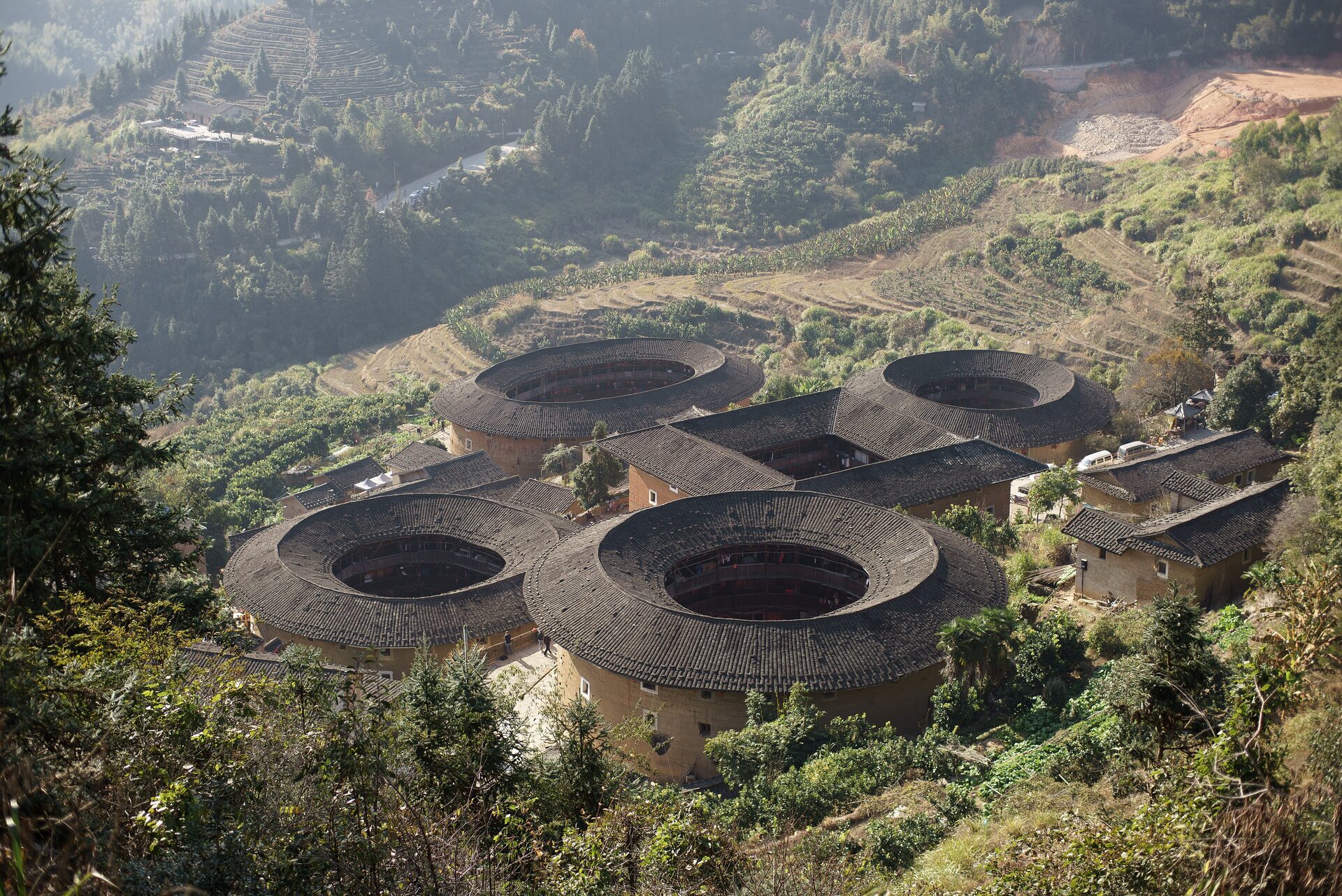 Round Fujian tulou earthen buildings with gray tile roofs seen from the hillside above Tianluokeng village