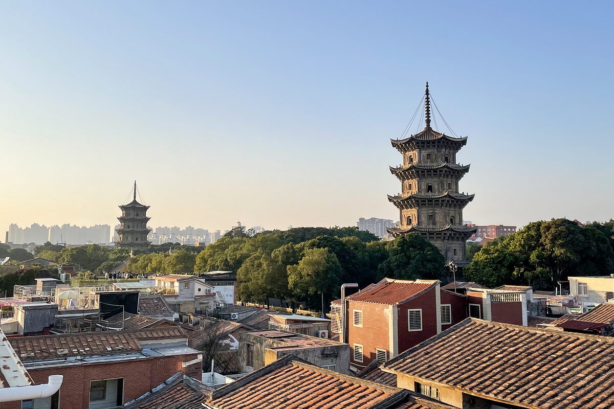 The two stone Twin Pagodas of Kaiyuan Temple rising above the tiled roofs of old Quanzhou at sunset