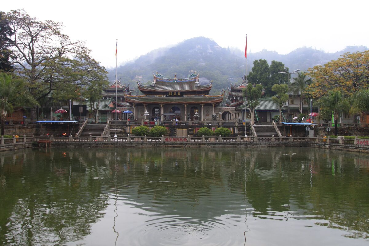 Nanputuo Temple seen across its reflecting pond, with a green hill rising behind