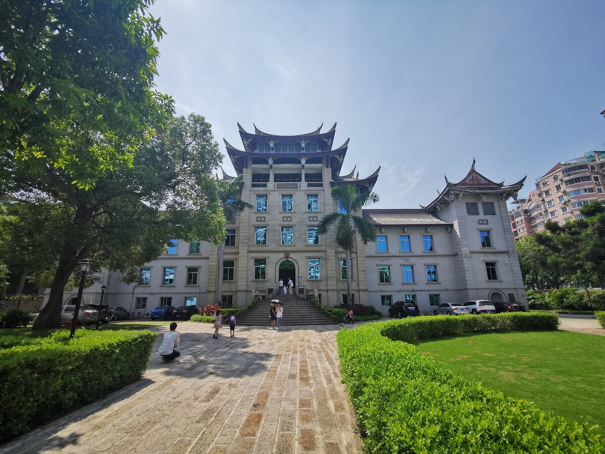 The main building of the Overseas Chinese Museum with upswept multi-tier roofs, seen across a lawn