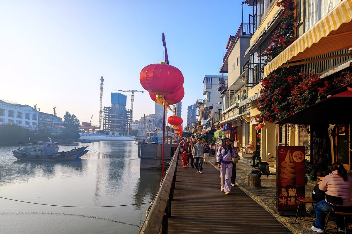 A wooden boardwalk with cafes and a red lantern beside the old fishing harbor at Shapowei