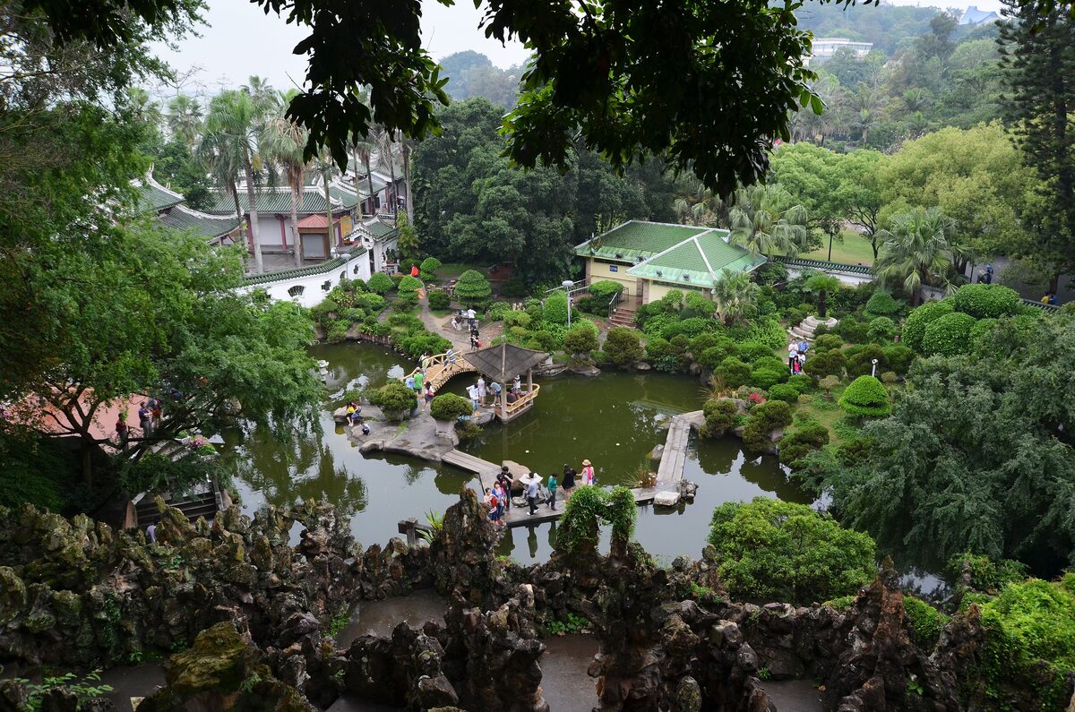 Pavilions and a small bridge among rockwork and trees around the pond at Shuzhuang Garden