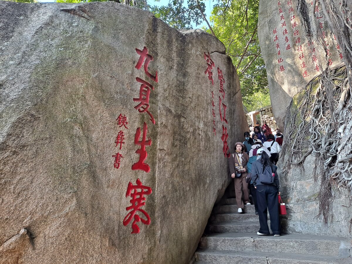 Red calligraphy carved into the granite of Sunlight Rock beside a narrow stairway