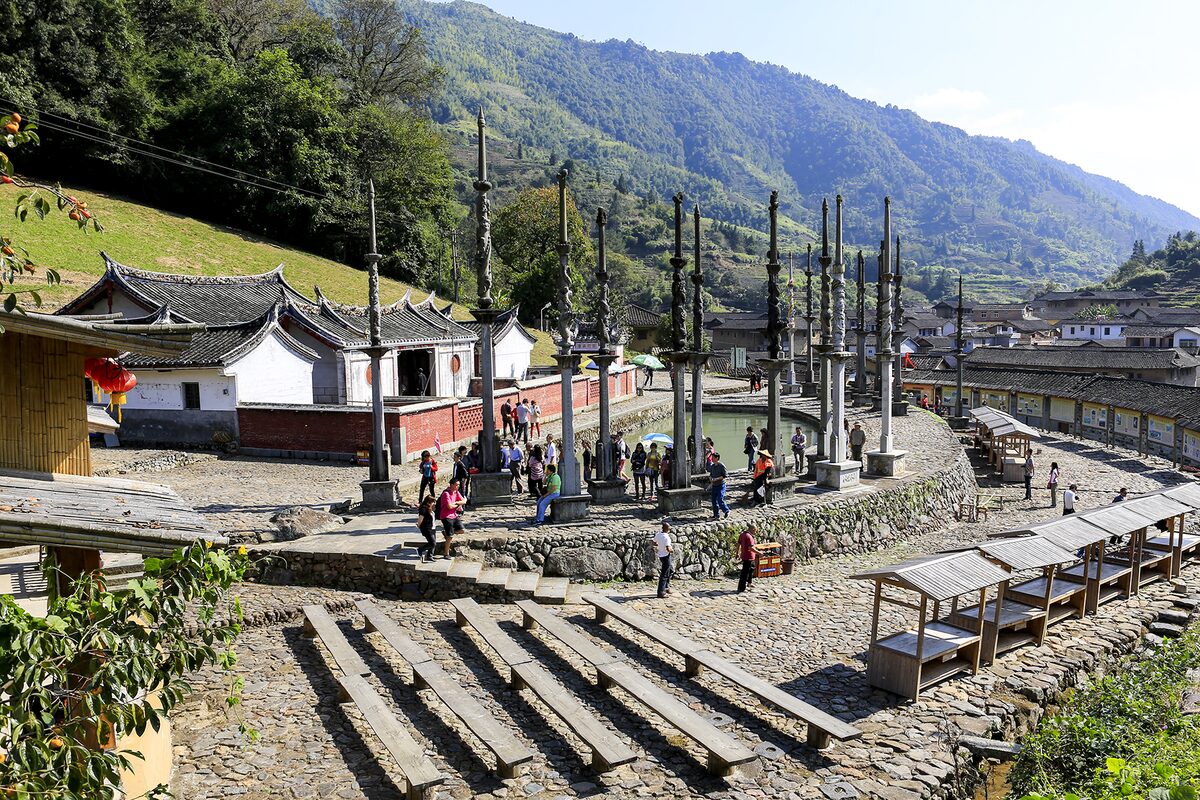 Deyuan Tang ancestral hall in Taxia village, with a row of stone flagpoles in front and hills behind