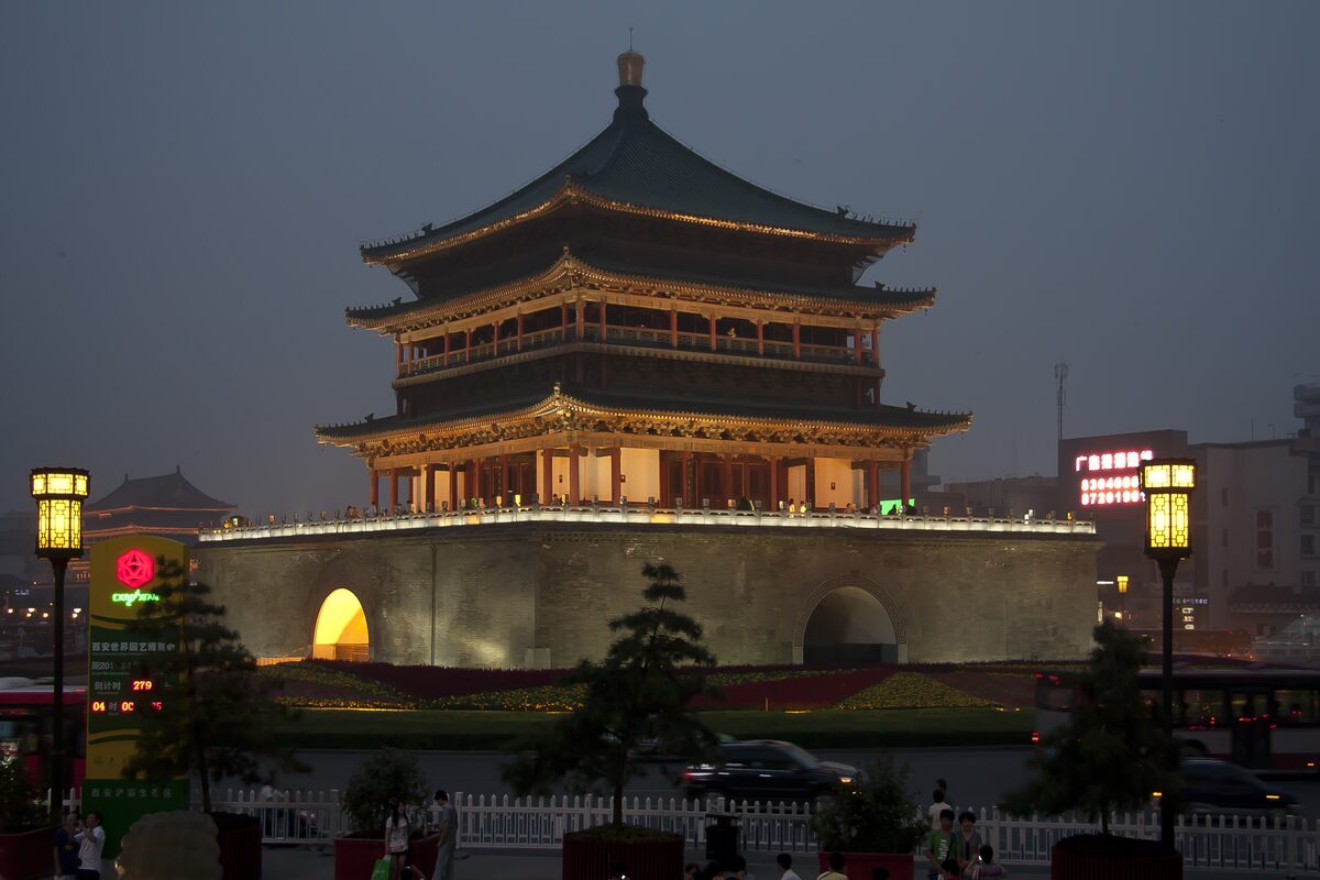 The Bell Tower of Xi'an at dusk, a three-tier wooden pavilion on a stone base in the middle of a traffic circle