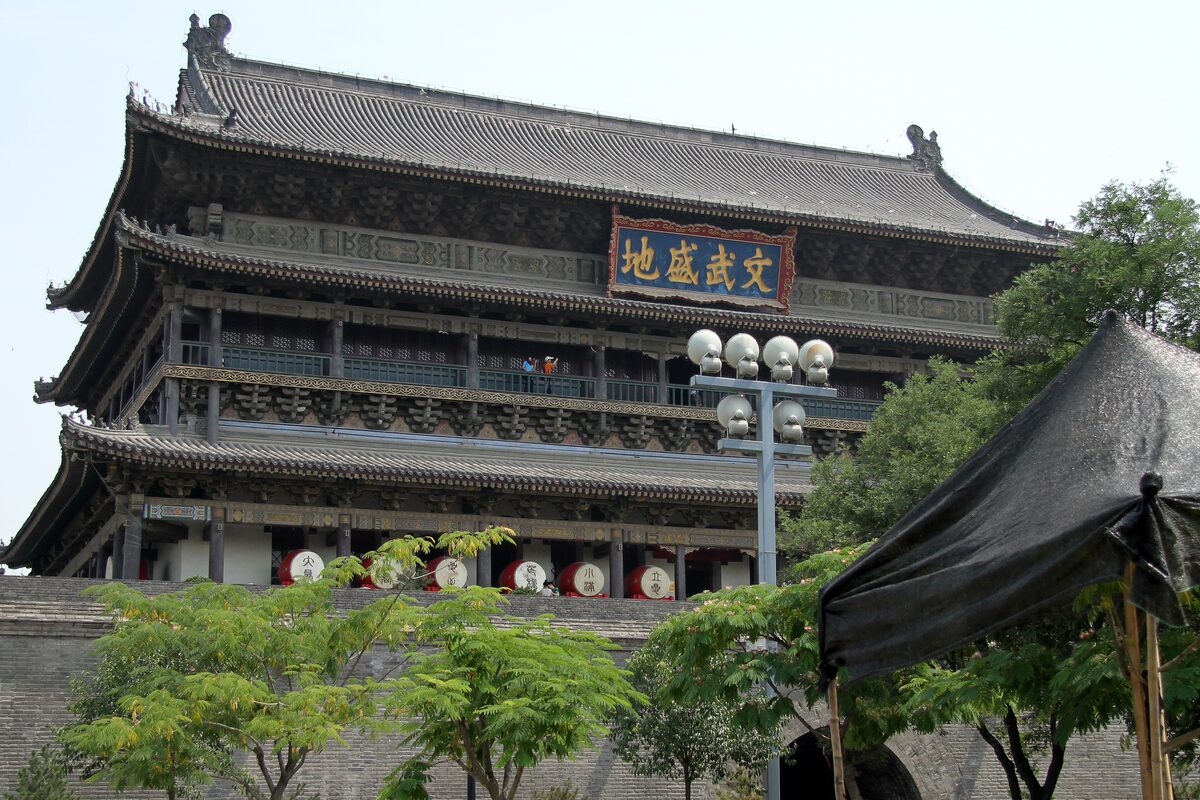The Drum Tower of Xi'an seen through trees, a two-tier wooden hall with a plaque under the upper eaves
