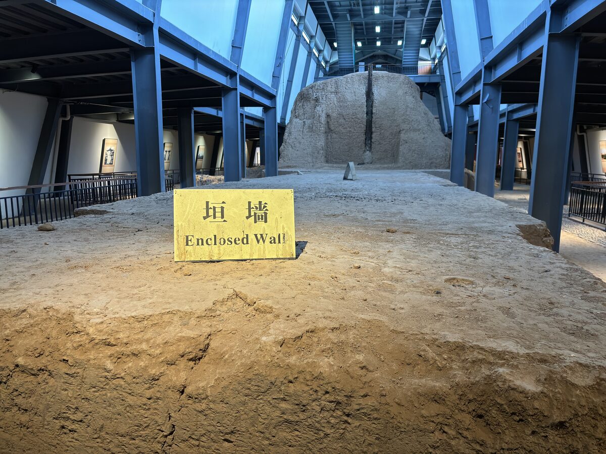An excavated section of rammed-earth enclosure wall under the protective hall at the Han Yangling Museum