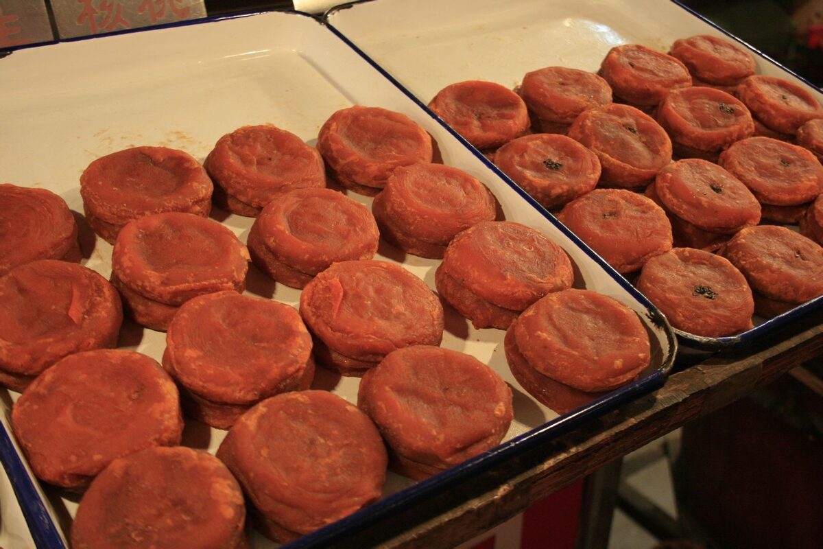 Two trays of round, red-brown shibing persimmon cakes in a bakery stall
