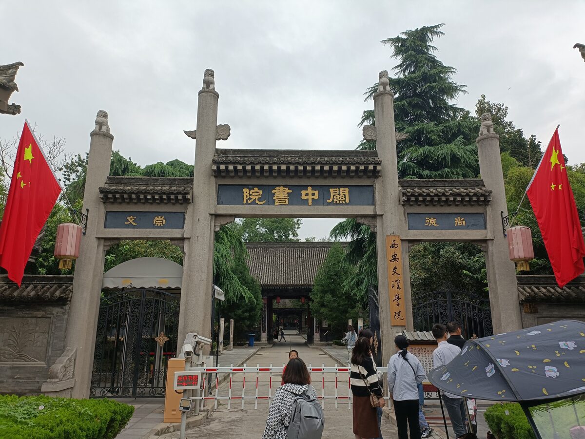 The stone archway gate of the Guanzhong Academy on Shuyuanmen street, with a red flag on each side